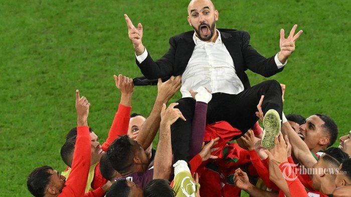 Para pemain Maroko melempar pelatih Maroko Walid Reragui ke udara saat mereka merayakan akhir pertandingan sepak bola babak 16 besar Piala Dunia Qatar 2022 antara Maroko dan Spanyol di Education City Stadium di Al-Rayyan, sebelah barat Doha. Selasa (6 Desember 2022).
