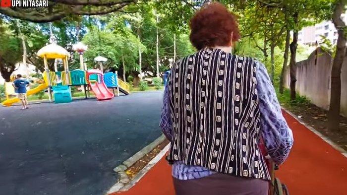 Majikan Upi latihan berjalan dengan mendorong kursi roda di taman