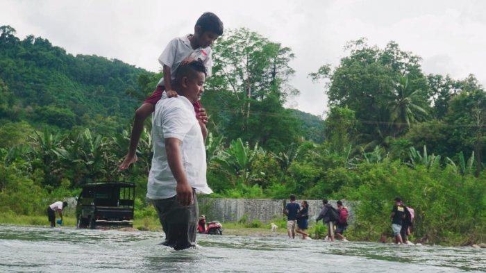 GENDONG - Warga gendong anak saat lintas Sungai Lowolaka di Desa Fataatu Timur, Kecamatan Wewaria, Kabupaten Ende, Pulau Flores, Provinsi Nusa Tenggara Timur, Februari 2022.