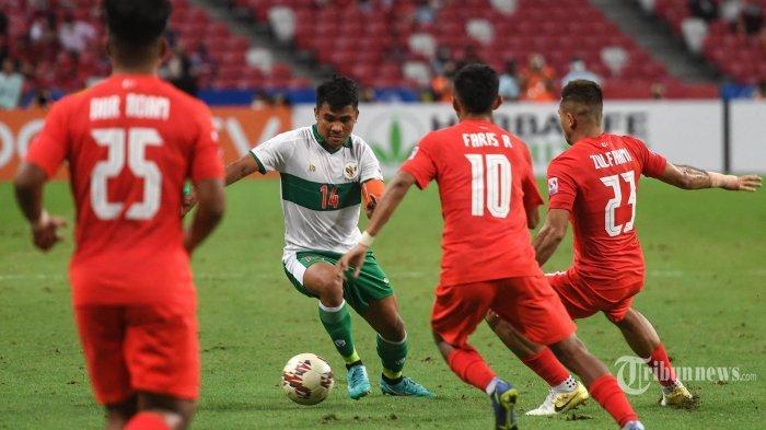 Asnawi Mangkualam Bahar (kedua dari kiri) berusaha menguasai bola melewati pemain Singapura Faris Ramli (kedua dari kanan) dan Zulfahmi Arifin (kanan) pada leg pertama pertandingan semifinal sepak bola AFF Suzuki Cup 2020 antara Singapura dan Indonesia di Stadion Nasional di Singapura pada 22 Desember 2021.
