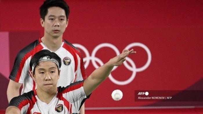 Petenis Indonesia Marcus Fernaldi Gideon (kiri) melakukan pukulan di sebelah Kevin Sanjaya Sukamuljo dari Indonesia dalam pertandingan penyisihan grup bulu tangkis ganda putra melawan Chirag Shetty dari India dan Satwiksairaj Rankireddy dari India selama Olimpiade Tokyo 2020 di Musashino Forest Sports Plaza di Tokyo pada 26 Juli, 2021.