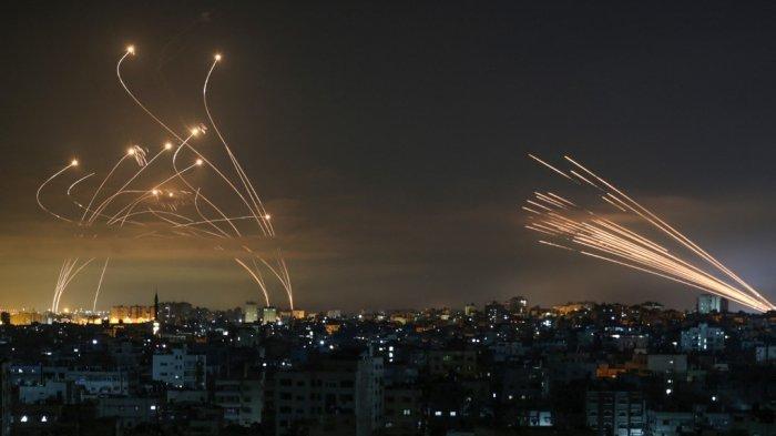 Sistem pertahanan rudal Iron Dome Israel (kiri) menangkal roket (kanan) yang ditembakkan oleh Hamas menuju Israel selatan dari Beit Lahia di Jalur Gaza 14 Mei 2021. Israel membombardir Gaza dengan artileri dan serangan udara pada hari Jumat, 14 Mei, sebagai tanggapan atas rentetan tembakan roket baru dari daerah kantong yang dikelola Hamas, tetapi menghentikan serangan darat dalam konflik yang kini telah merenggut lebih dari 100 nyawa warga Palestina.