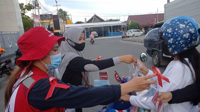 Relawan PMI cabang Nunukan sedang membagikan leaflet HIV AIDS, masker dan hand sanitizer, dan pita merah kepada setiap pengendara yang lewat di Alun-alun Nunukan, Kalimantan Utara, Selasa (1/12/2020), pukul 17.30 Wita. TRIBUNKALTARA.COM/ Febrianus Felis