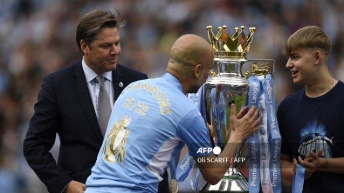 Manager Manchester City, Pep Guardiola melihat trofi Liga Inggris. Hasil Liga Inggris, Manchester City juara Liga Inggris. Liverpool gagal angkat trofi meski menang atas Wolves.