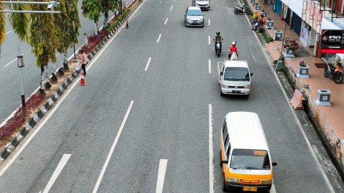 Angkot melintas di jalan raya mencari penumpang.