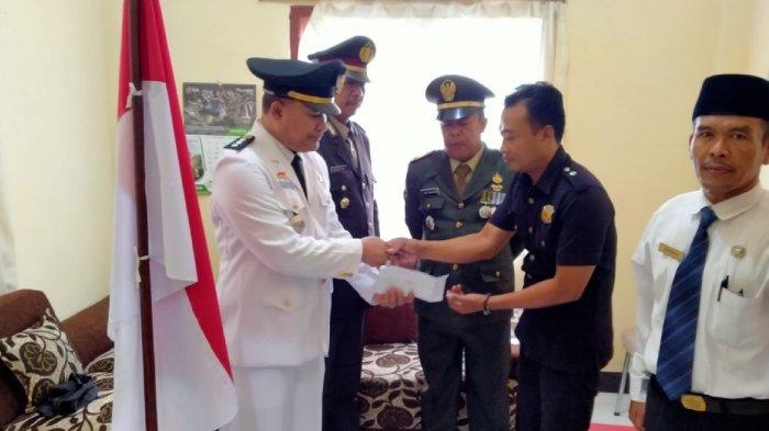 Camat Keruak Ahmad Subhan (kiri) memberikan apresiasi dalam bentuk uang kepada Satpam Puskesmas Keruak Zulkarnaen yang melakukan aksi heroik, saat upacara bendera HUT RI ke-77, Rabu (17/8/2022).