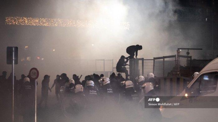 Petugas polisi anti huru hara Belgia bentrok dengan pengunjuk rasa setelah tim sepak bola Maroko kalah dalam pertandingan sepak bola semifinal Piala Dunia 2022 melawan Prancis, di Brussel pada 14 Desember 2022.
