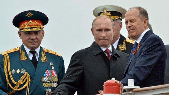 Presiden Rusia Vladimir Putin (tengah) meninjau kapal angkatan laut Rusia di pelabuhan Sevastopol di Krimea pada 9 Mei 2014, dengan dihadiri oleh Kepala Dinas Keamanan Federal (FSB) Alexander Bortnikov (kanan) dan Menteri Pertahanan Sergei Shoigu (kiri).