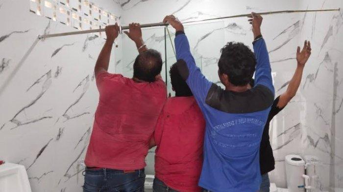 Empat pekerja pria pemasang kaca terlihat membuat sekat di toilet kantor DPRD Deli Serdang Rabu, (7/12/2022).
