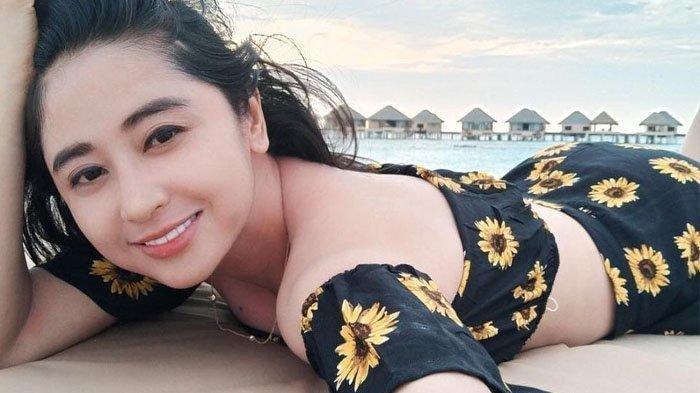 Bentuh tubuh Dewi Perssik saat tiduran di pasir pantai.
