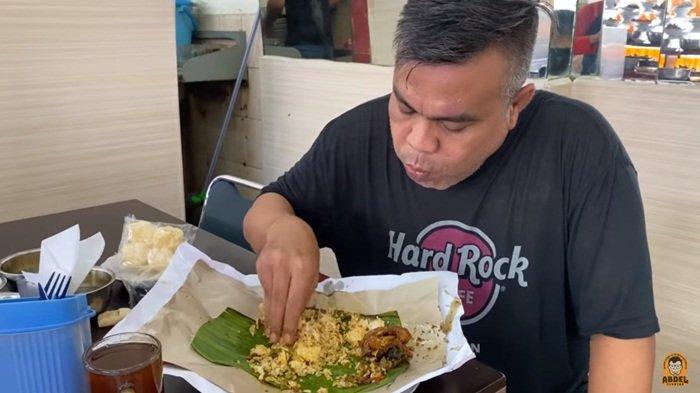 Komedian Abdel Achrian menikmati sebungkus nasi padang.