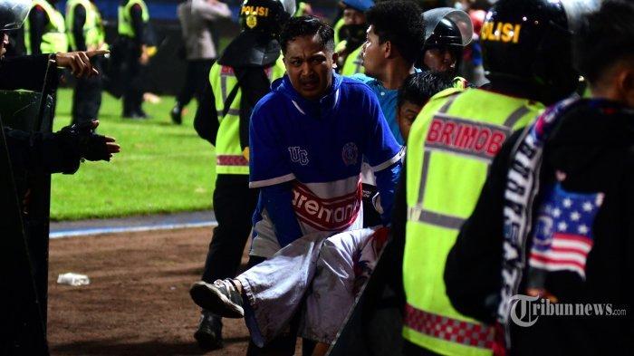 Sejumlah suporter Arema FC, Aremania menggotong korban kerusuhan sepak bola usai laga lanjutan BRI Liga 1 2022/2023 antara Arema FC melawan Persebaya Surabaya di Stadion Kanjuruhan, Kabupaten Malang, Jawa Timur, Sabtu (1/10/2022) malam. Sebanyak 127 orang meninggal dunia dan ratusan lainnya luka-luka dalam kerusuhan tersebut menyusul kekalahan Arema FC dari Persebaya Surabaya dengan skor 2-3.