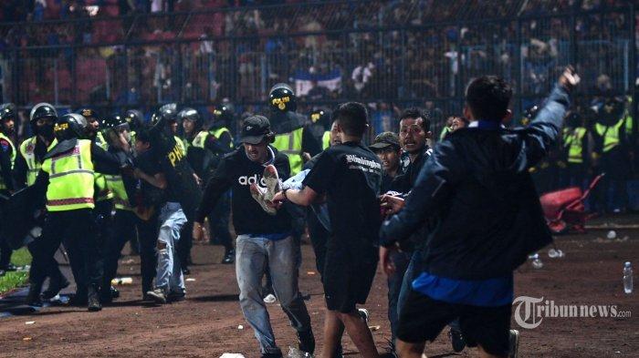 Dalam foto yang diambil pada 1 Oktober 2022 ini, sekelompok orang menggendong seorang pria usai pertandingan sepak bola antara Arema FC dan Persebaya Surabaya di Stadion Kanjuruhan, Malang, Jawa Timur. - Sedikitnya 127 orang tewas di sebuah stadion sepak bola di Indonesia pada akhir 1 Oktober ketika para penggemar menyerbu lapangan dan polisi merespons dengan gas air mata, yang memicu penyerbuan, kata para pejabat. (Photo by AFP)