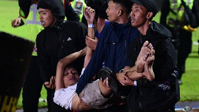 Sekelompok orang membawa seorang pria di Stadion Kanjuruhan di Malang, Jawa Timur, Sabtu (1/10/2022) malam. Rusuh terjadi setelah laga Arema FC Vs Persebaya Surabaya dengan skor 2-3