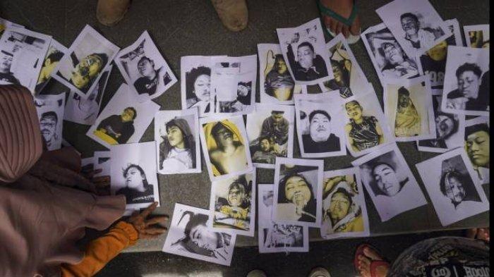 Orang-orang memeriksa kumpulan foto korban tragedi di Stadion Kanjuruhan