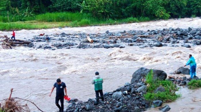 Warga berusaha mengevakuasi korban terjebak aliran sungai meluap