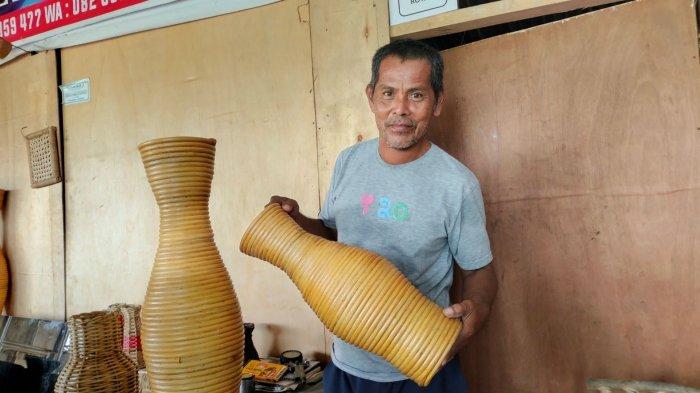 Baharuddin sedang memperlihatkan guci vas bunga yang terbuat dari rotan