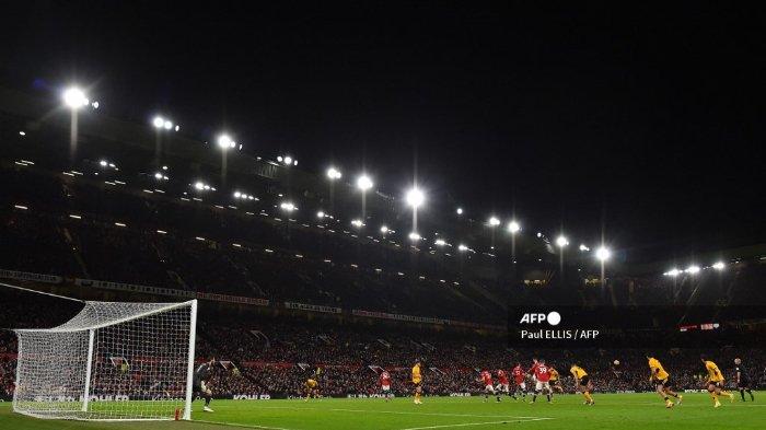 Para pemain bersaing memperebutkan bola di bawah lampu sorot selama pertandingan sepak bola Liga Premier Inggris antara Manchester United dan Wolverhampton Wanderers di Old Trafford di Manchester, barat laut Inggris, pada 3 Januari 2022.