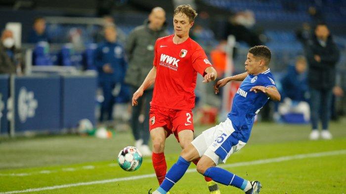 Bek Augsburg Polandia Robert Gumny (kiri) dan gelandang Schalke Prancis Amine Harit berebut bola selama pertandingan sepak bola divisi satu Bundesliga Jerman antara FC Schalke 04 dan FC Augsburg di Gelsenkirchen, Jerman Barat, pada 11 April 2021.