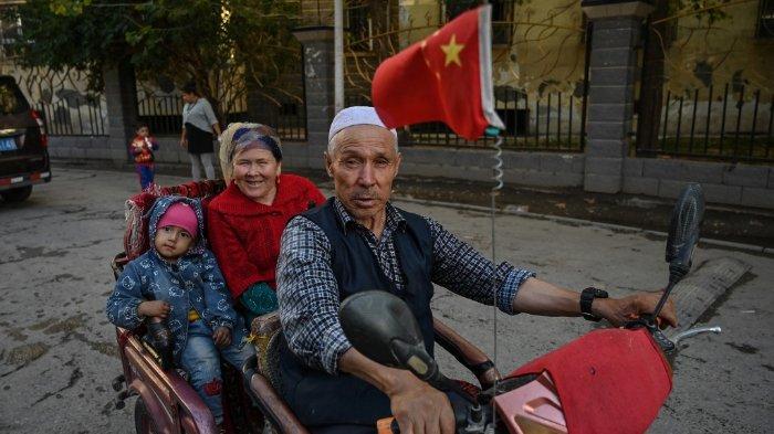 Foto ini diambil pada 11 September 2019 menunjukkan seorang pria mengendarai kendaraan di lingkungan etnis Uighur di Aksu, Xinjiang. Otoritas China melakukan sterilisasi paksa terhadap perempuan dalam opersi menahan pertumbuhan populasi etnis minoritas di wilayah Xinjiang barat, menurut penelitian yang diterbitkan pada 29 Juni 2020.