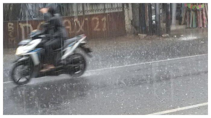 Seorang pengendara sepeda motor menerjang hujan