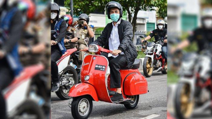 Walikota Dumai Paisan mengendarai vespa merah saat berkunjung ke rumah warga untuk membagikan sembako