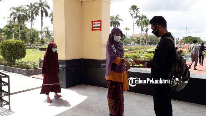 Pengunjung Istana Siak sedang dicek suhu tubuhnya sebelum masuk ke sitana oleh petugas.